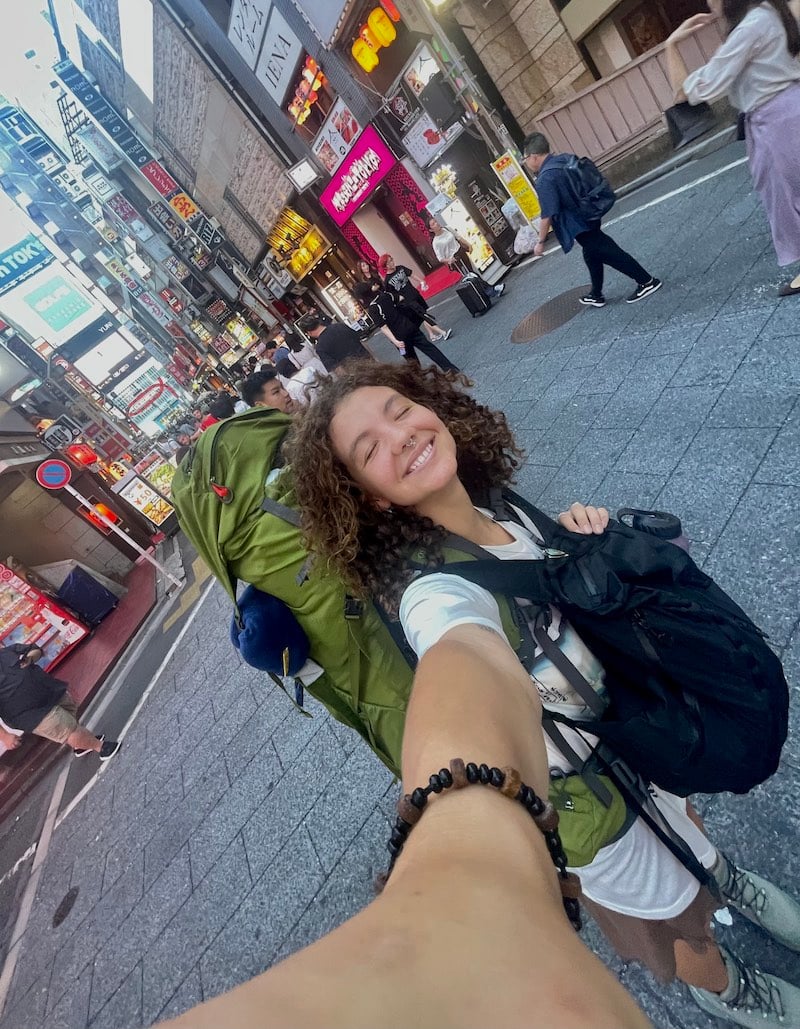 Girl is smiling as she backpacks the streets of Tokyo Japan.
