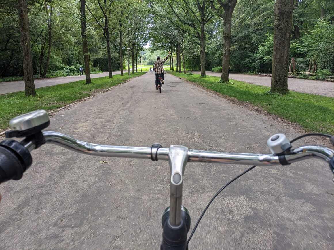 Riding a bike through park in The Netherlands with person fist pumping ahead