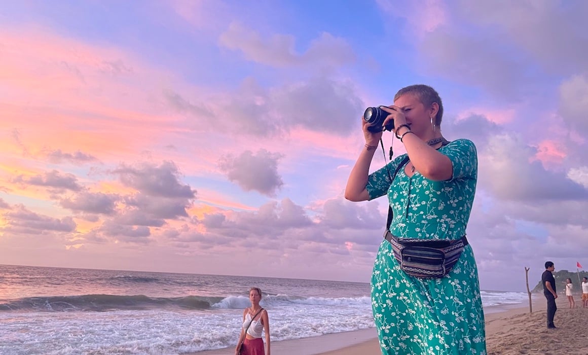 Girl takes photo of the colorful sunset that lines the beaches of Sayulita, Mexico.