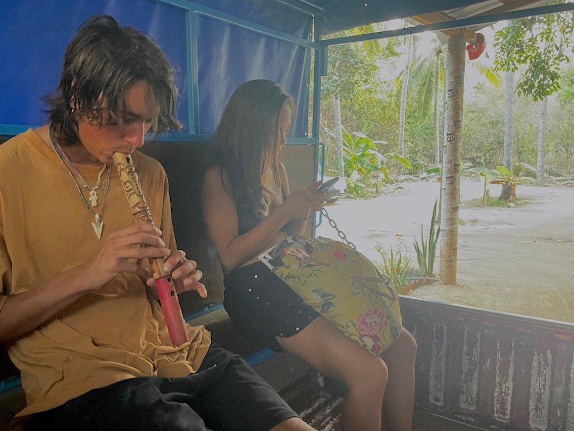 Man plays flute in the back of a truck in Zipolite, Mexico.