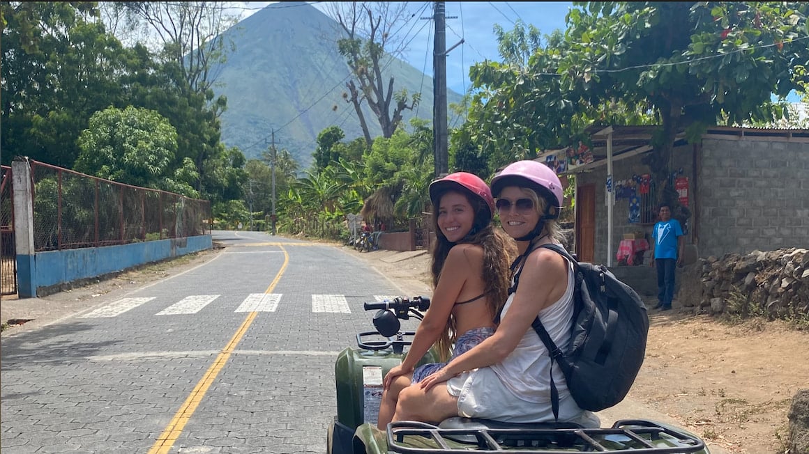two girls on an ATV exploring Ometepe, Nicaragua with a view of a volcano
