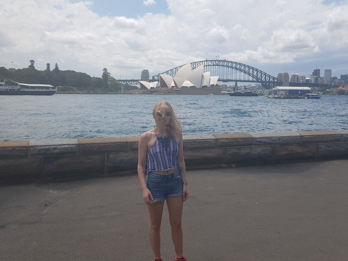 Laura with her hair blown in the wind with Sydney Opera House in the background on a cloudy day