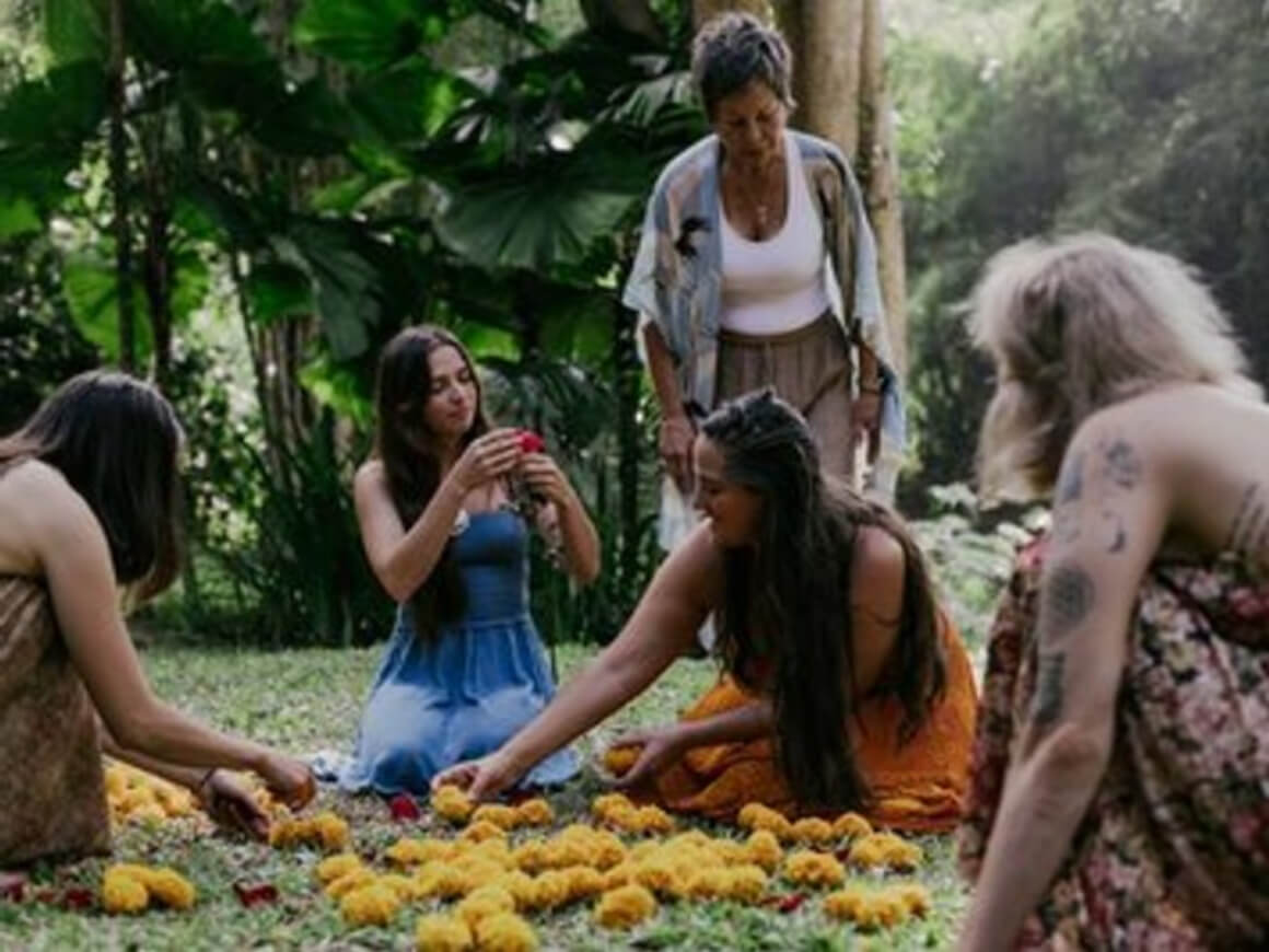 A gathering of young women adorned in bohemian dresses, collecting flowers.