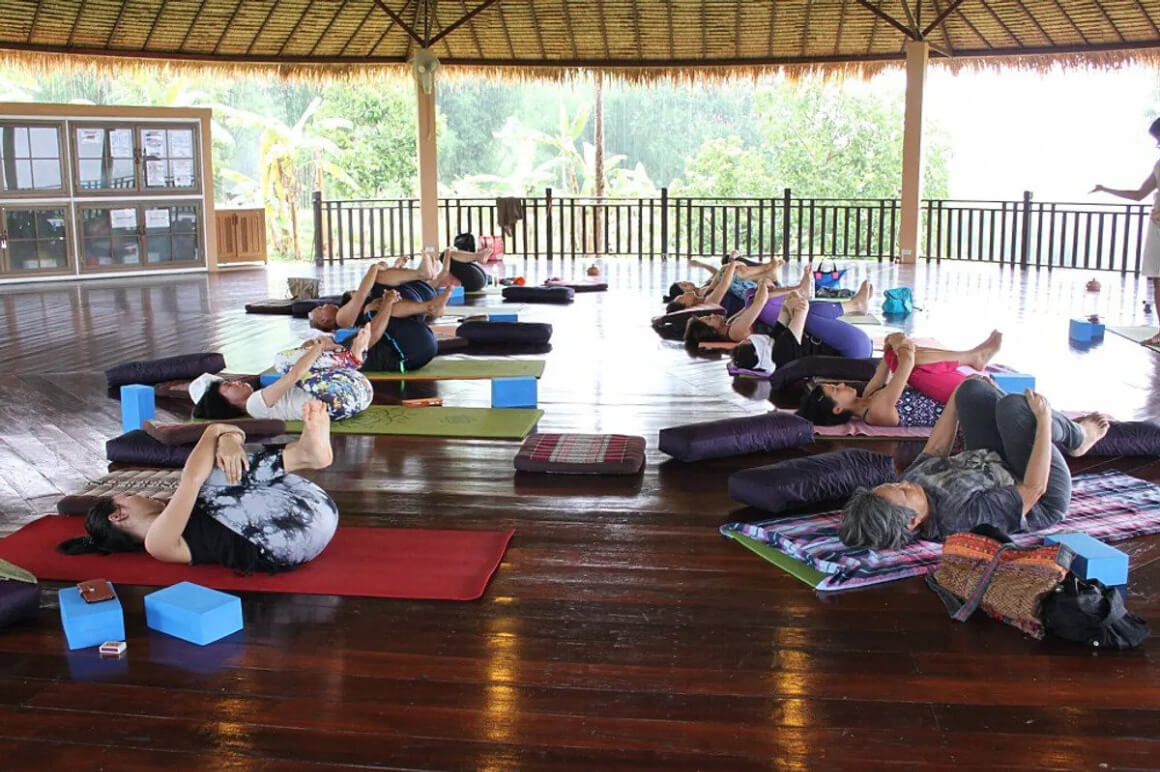 A community of individuals reclining on their yoga mats, engaged in a yoga session.