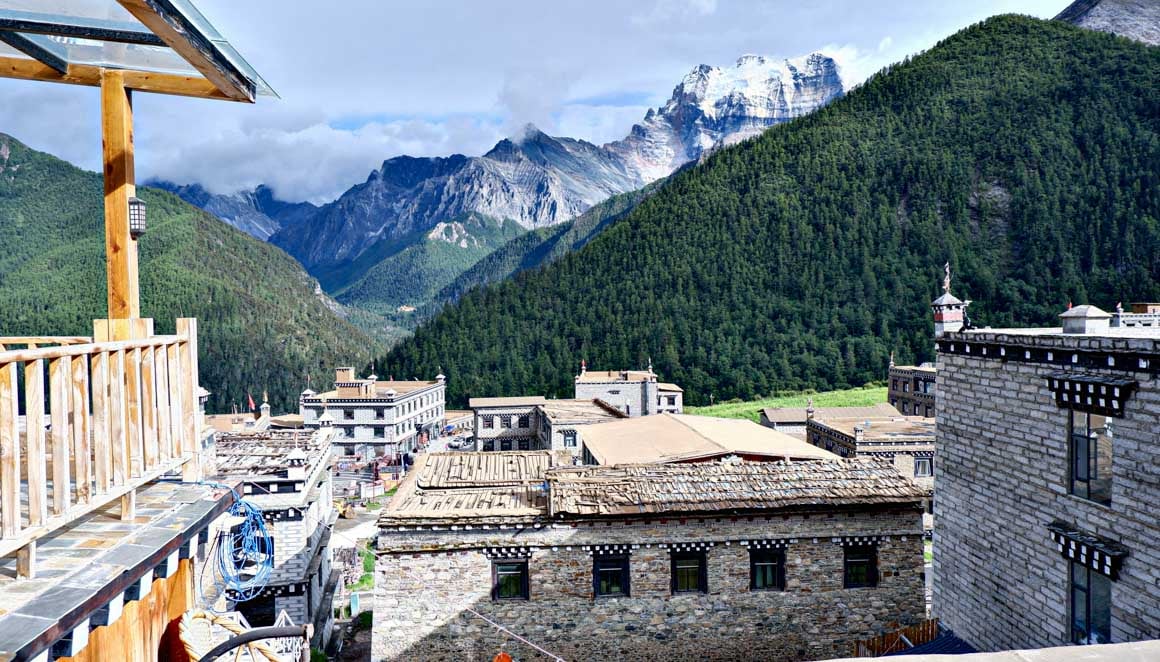 A photo of snow-capped mountains and traditional Tibetan houses