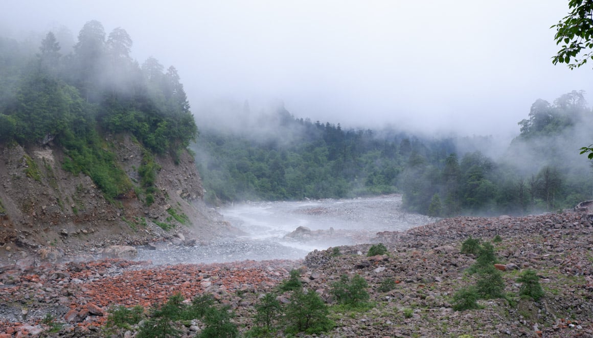 A landscape of the red rock shoal covered in mist in HaiLuoGou national park
