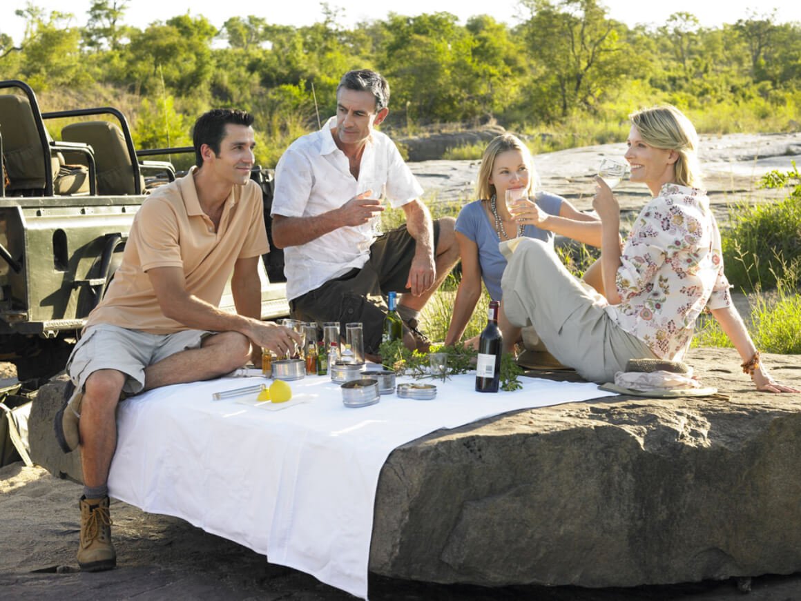 Four people enjoying wine and picnic on a rock