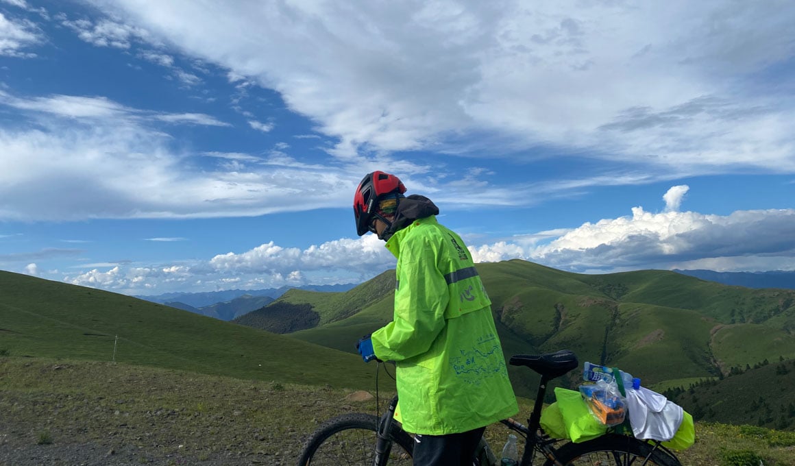 A person pushing their bike up a hill on their way to Tibet