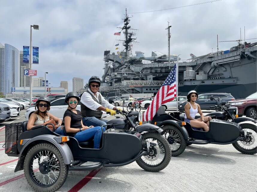 A group of tourists on a tandem sidecar tour with an American flag in San Diego