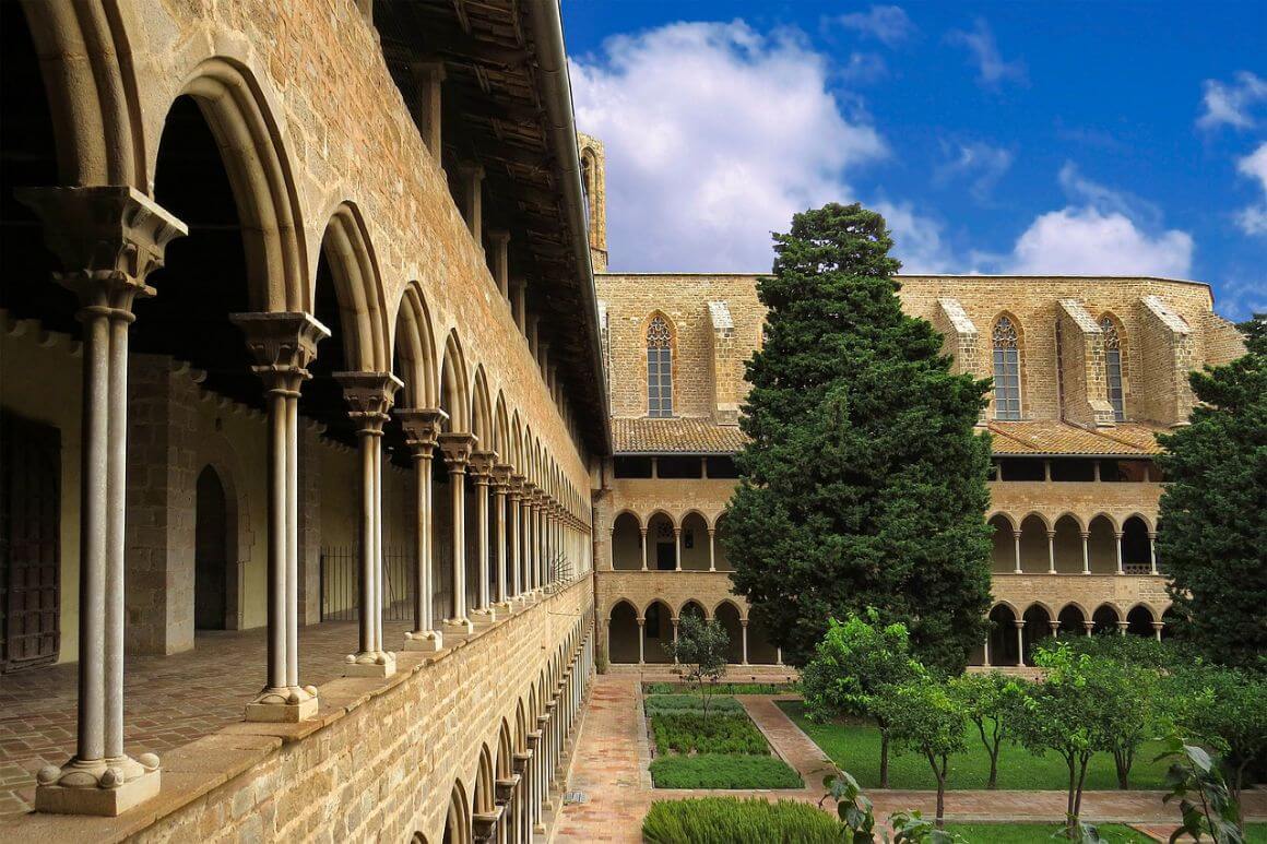 A building with arches overlooking a large courtyard with trees in Barcelona