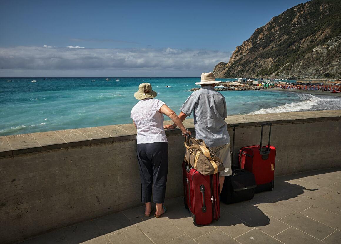 A couple with their baggage looking at the sea 