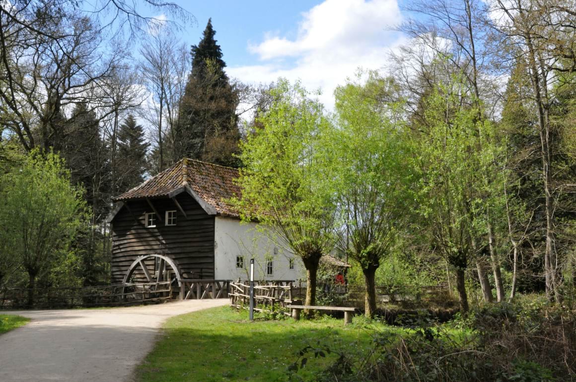 A wooden house with a water wheel in the middle of a forest in Bokrijk, belgium