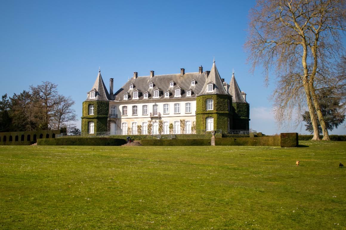 Chateau de la Hulpe surrounded with a green valley and trees 