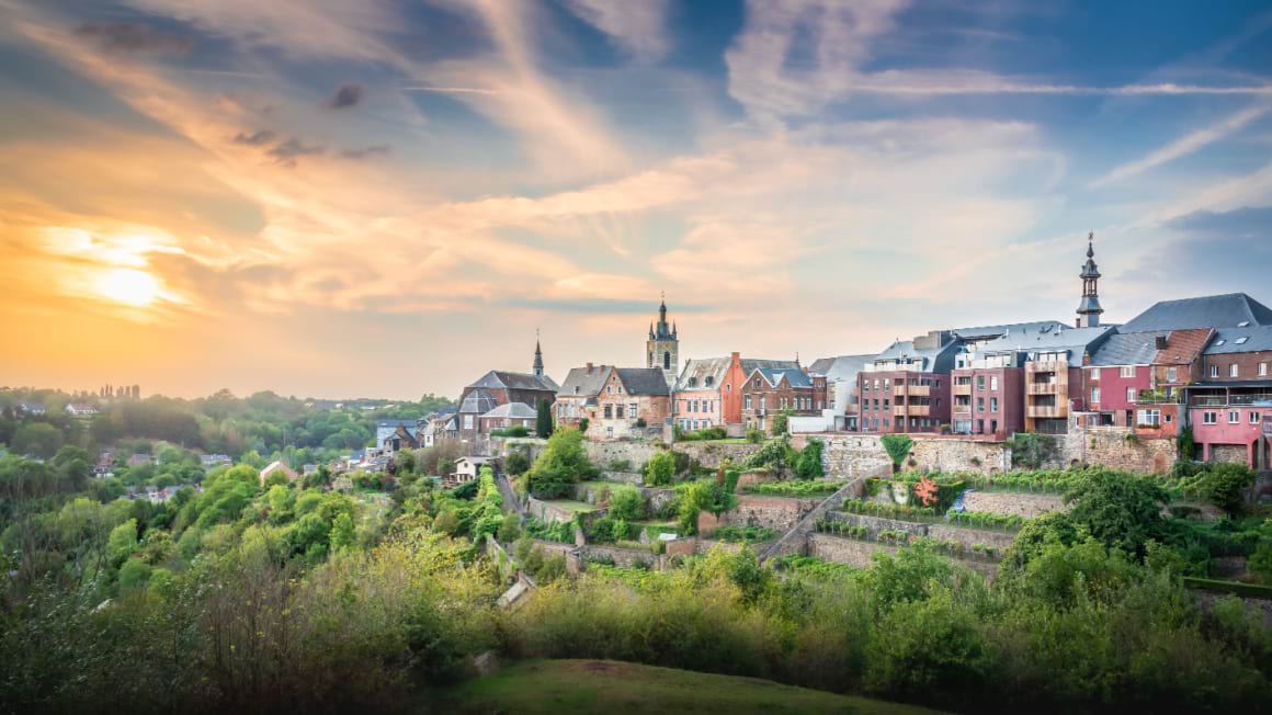 A landscape view of Thuin's Hanging Gardens with buildings, three towers in the backdrop