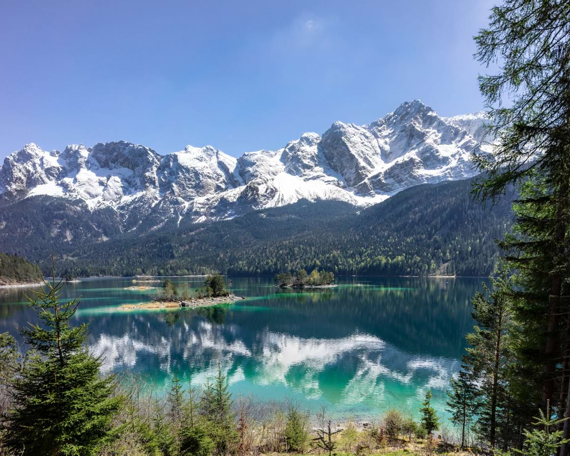 A lake with snow-capped peaks mountains in the background in Eibsee