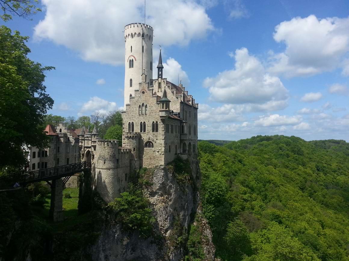 Lichtenstein castle sitting on top of a cliff in the middle of a lush forest 