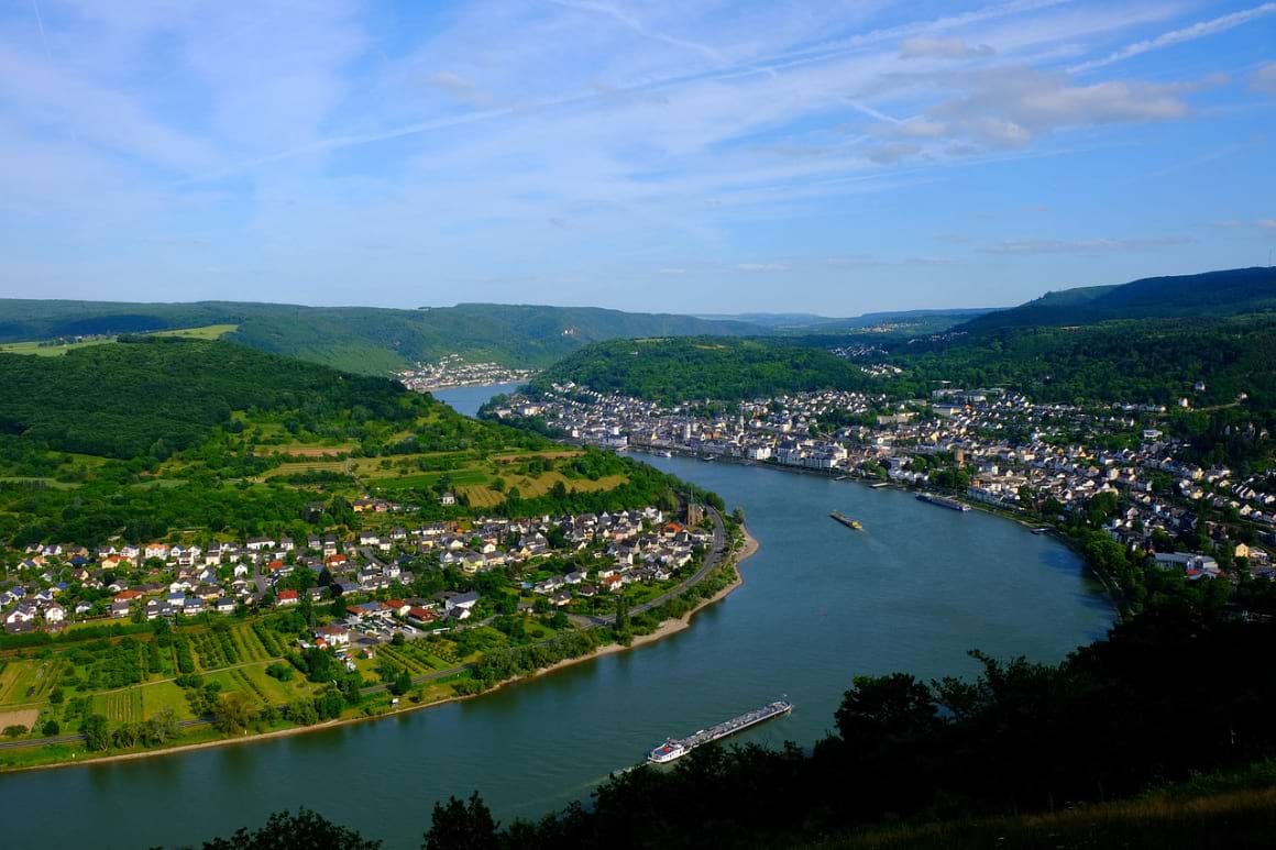 A landscape view of the Rhine River lined by lush greenery with villages overlooking the river