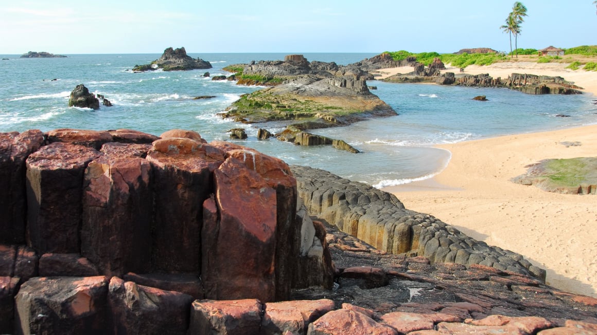 reddish black columns of basalt lava rock scattered about a coastline on one of the best islands in india