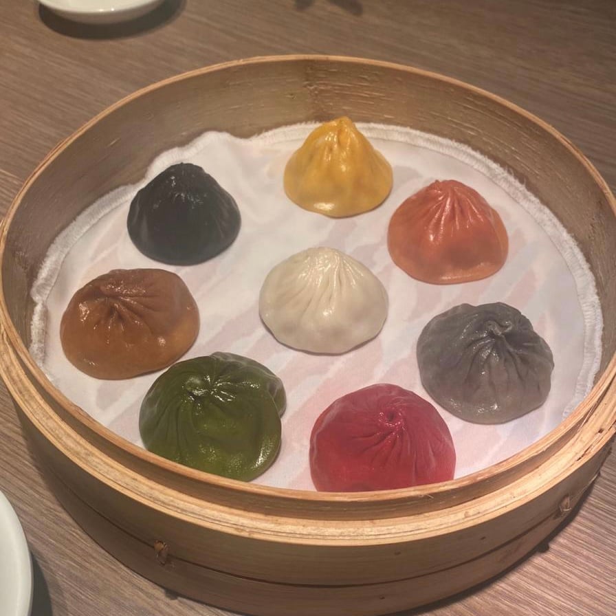 eight dumplings all in different colors in a circular wooden bowl in hong kong