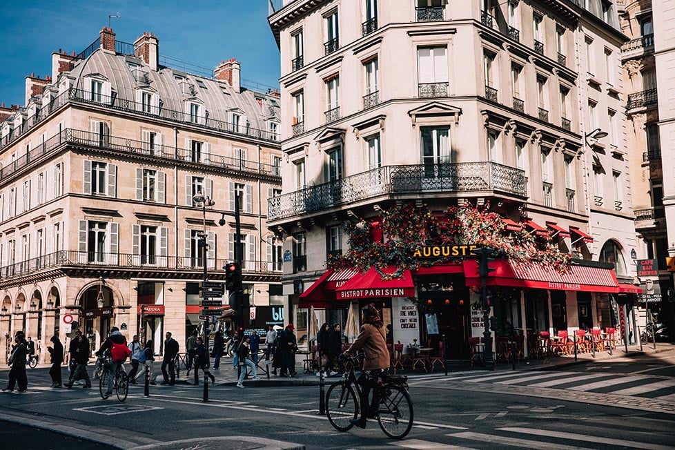 A person riding past a floral cafe on the streets of Paris