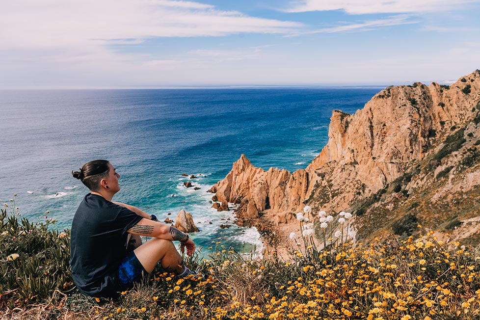 A person looks out over the rocky cliffs of Portugal