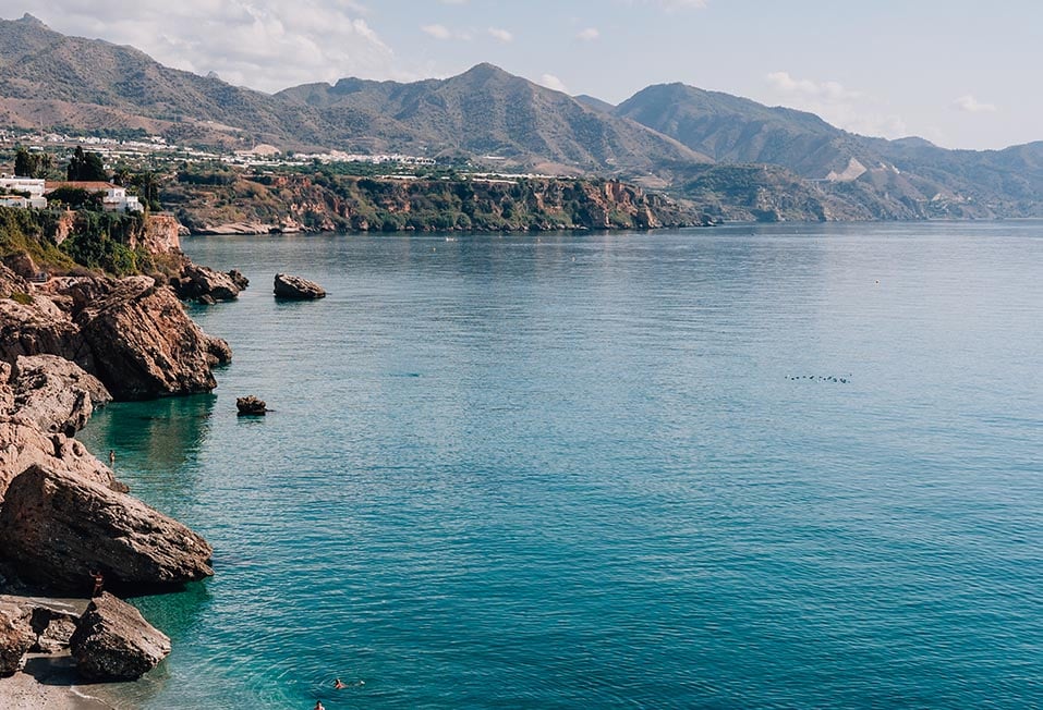 A rocky beach and coastline with mountains in the background