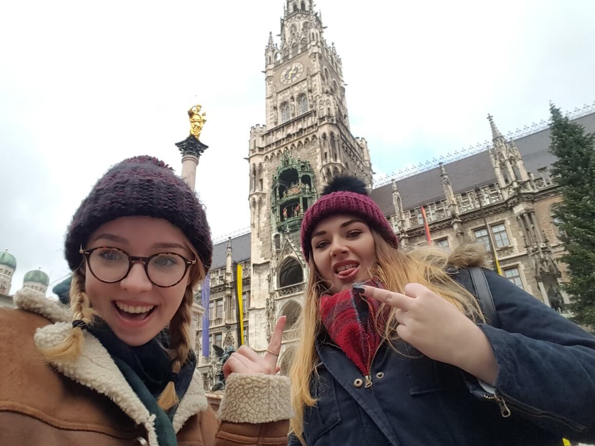 2 women posing at the camera in warm clothes front of the Rathaus in Munich