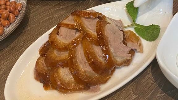 glazed roast duck on a white oval shaped plate hong kong food