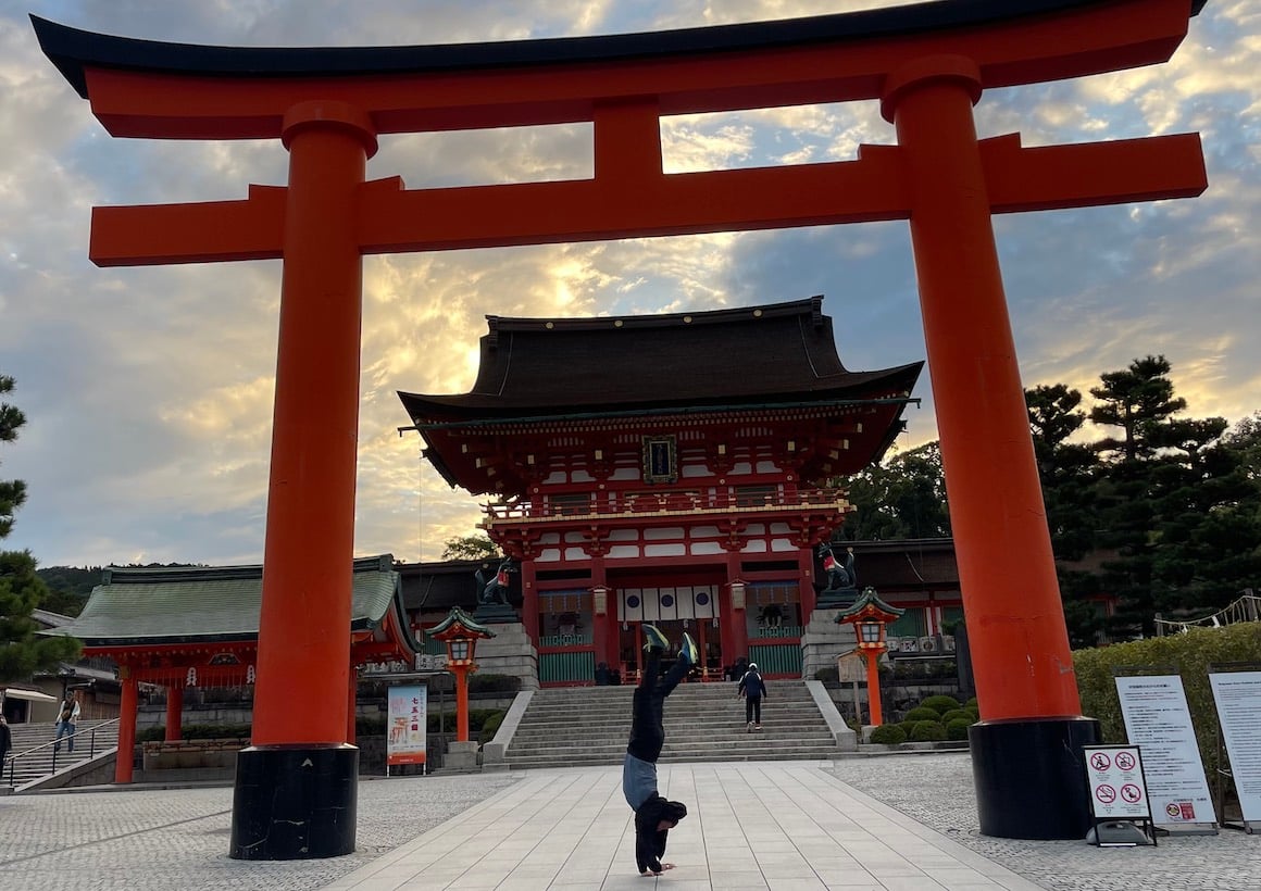 Guy does handstand under shrine in Kyoto, Japan.