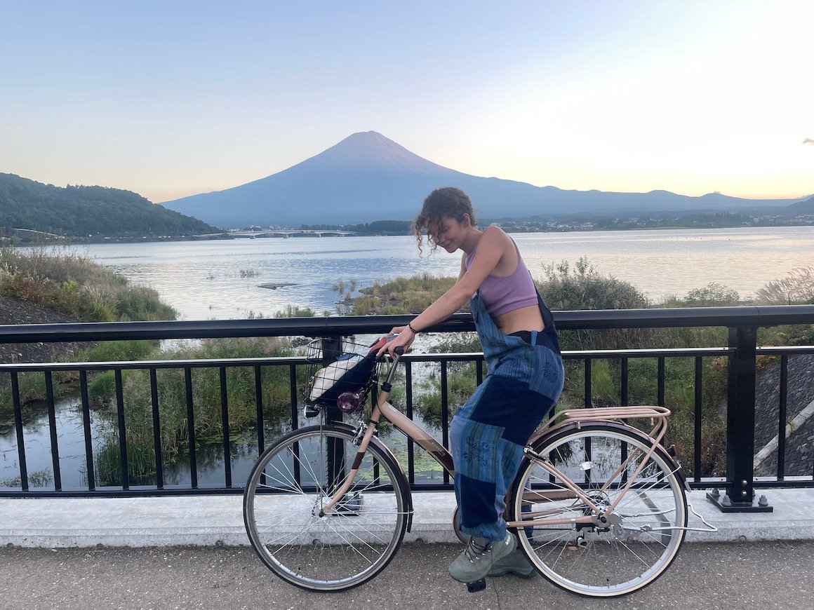 Girl rides bike across a bridge by Lake Kawaguchiko in Japan.