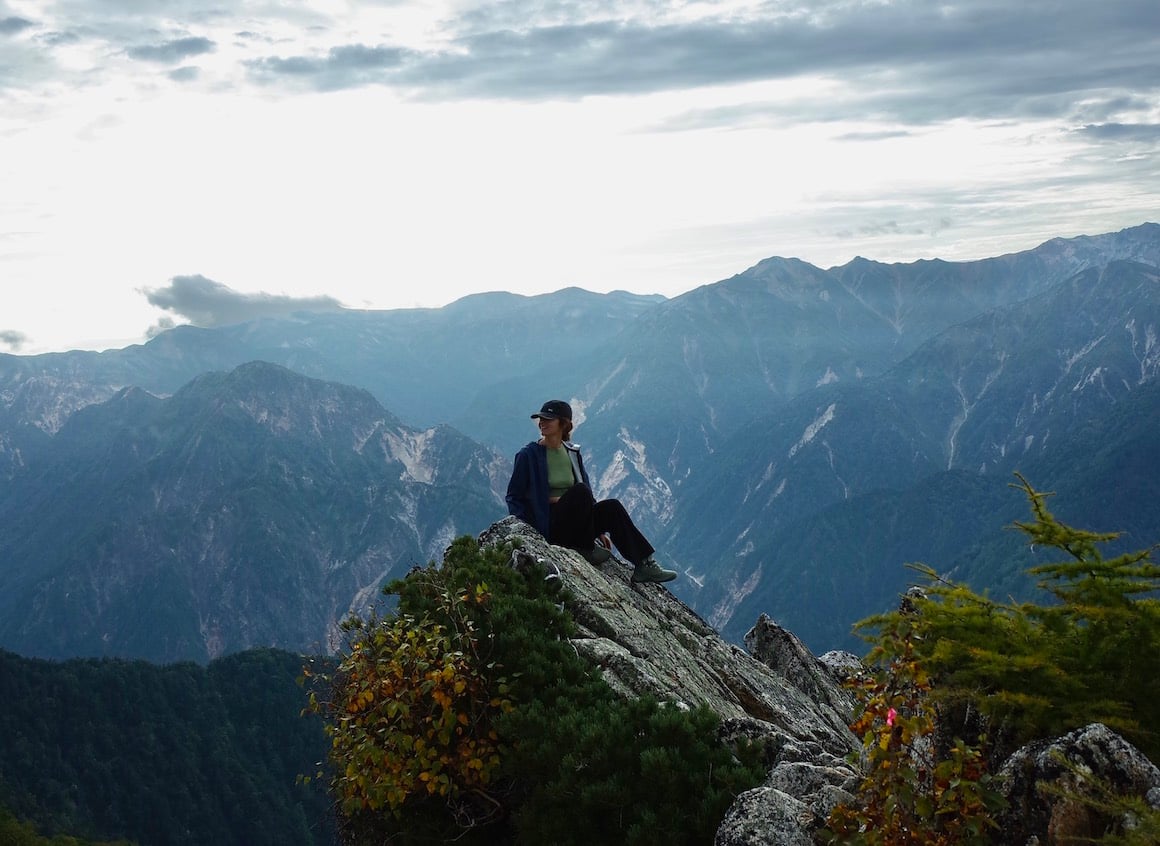 Girl poses for photo on top of mountain in Japanese Alps.