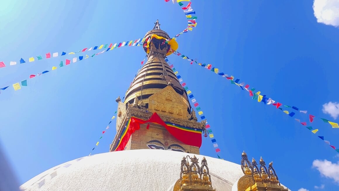 Worm's eye view of Boudhanath temple in Kathmandu in front of a perfectly blue sky.