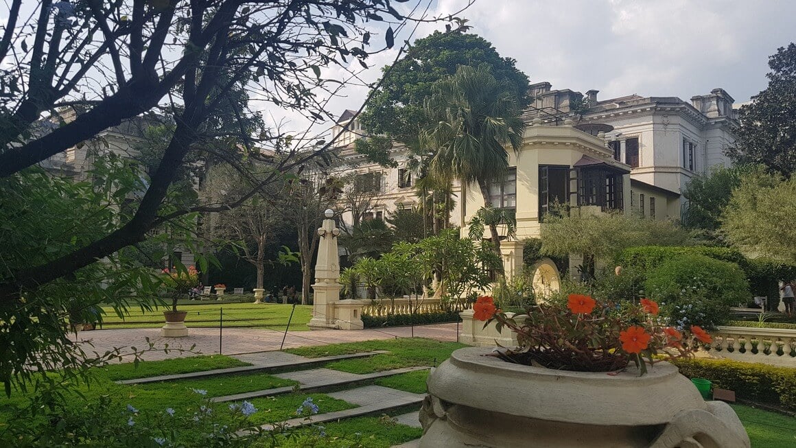 Garden of Dreams in Kathmandu city centre building with plants in foreground on a cloudy day.