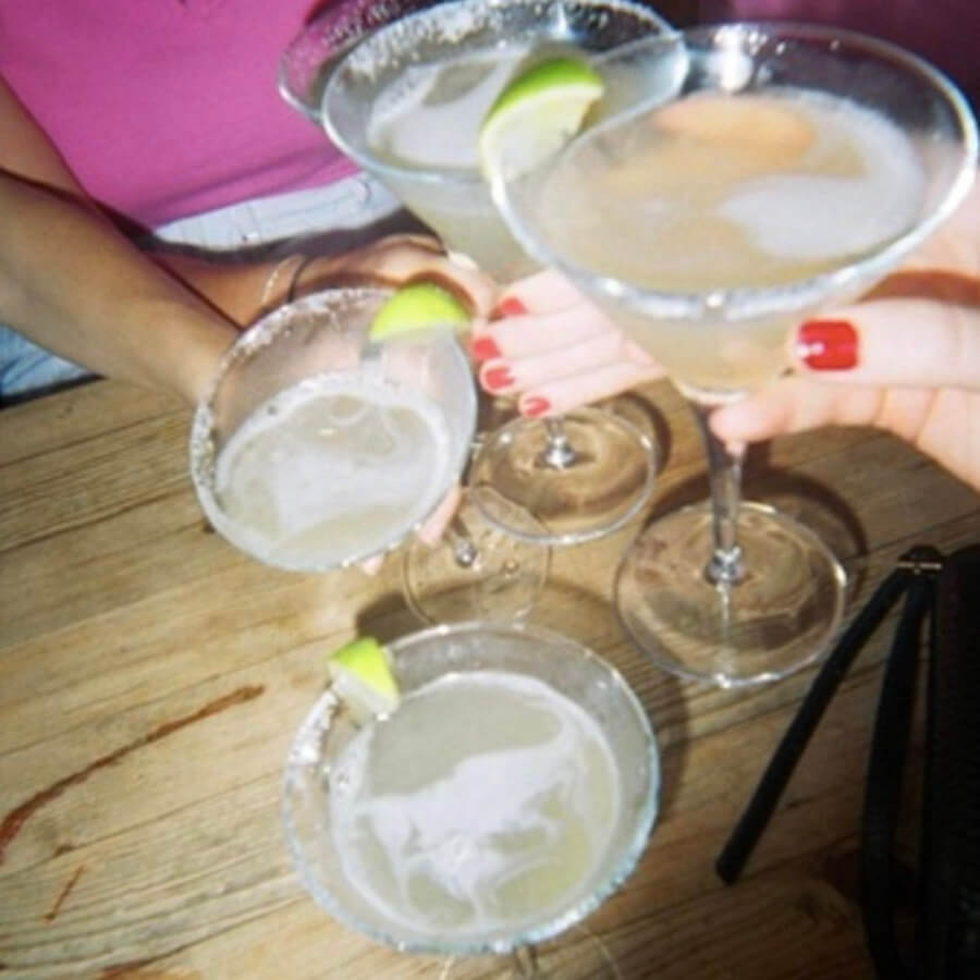 Four margarita cocktails cheersing on a night out.  