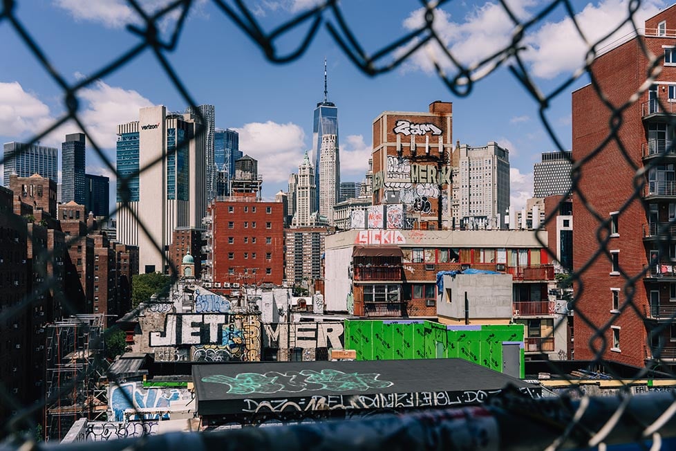 Looking through the broken fence on the Manhattan Bridge of buildings covering in graffiti in lower Manhattan