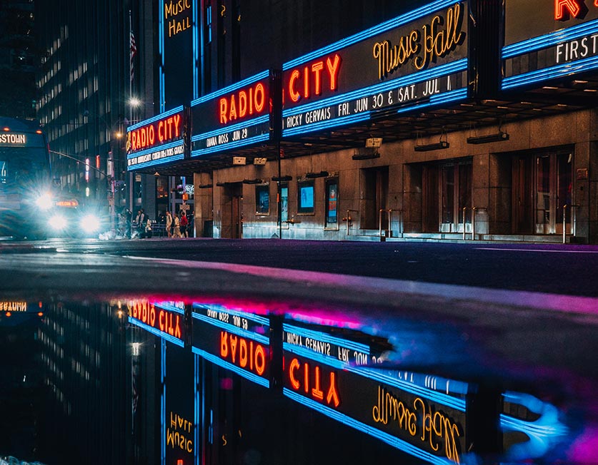 The lights of Radio City reflecting in a puddle at night