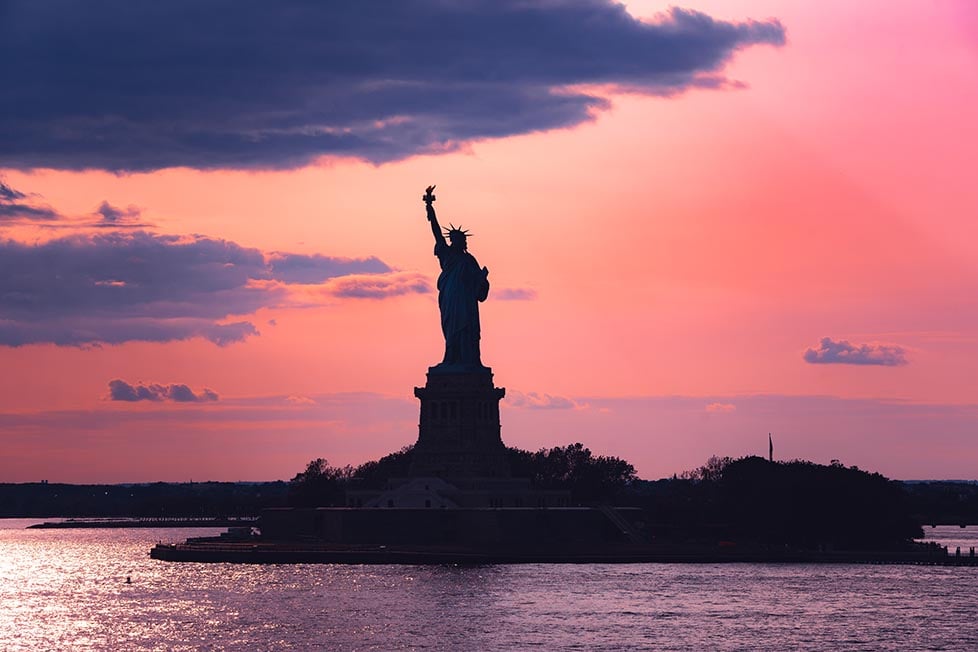 The Statue of Liberty with the sunsetting in the background