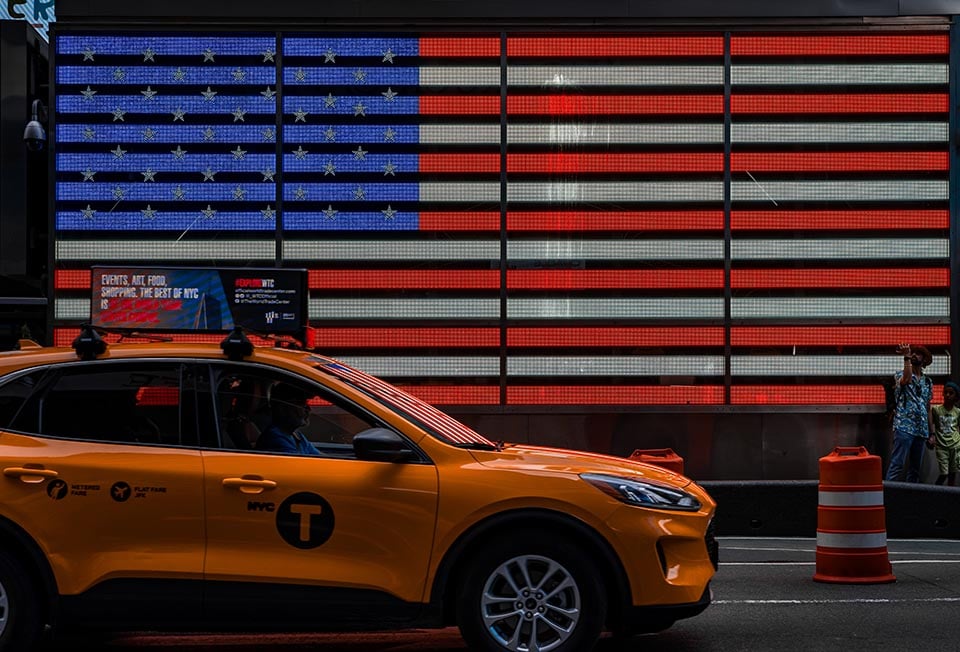 An American flag and yellow NYC taxi cab