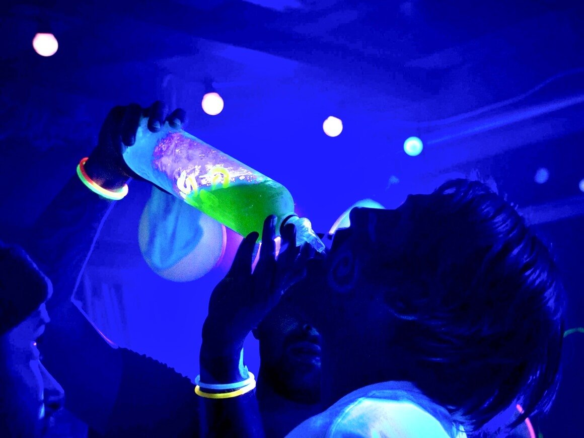 People drinking from a bottle at the club during a party night.
