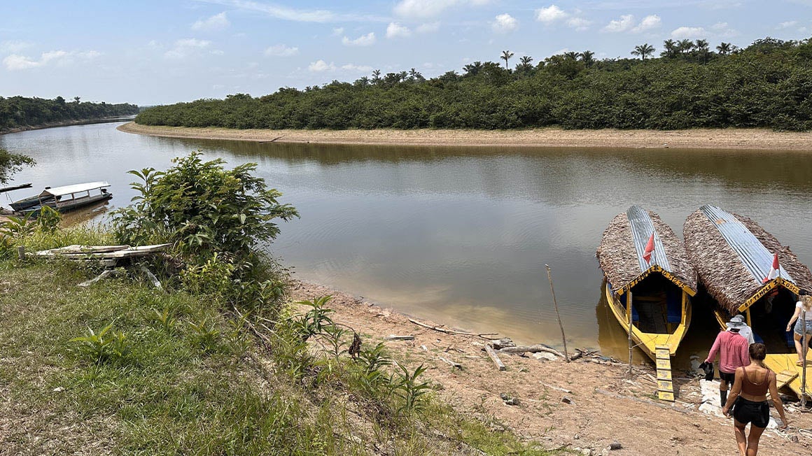 Travelers heading to Amazon boarding boat canoe in Iquitos river beach.