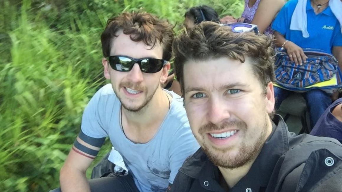Will and Alex smiling on a moving bus