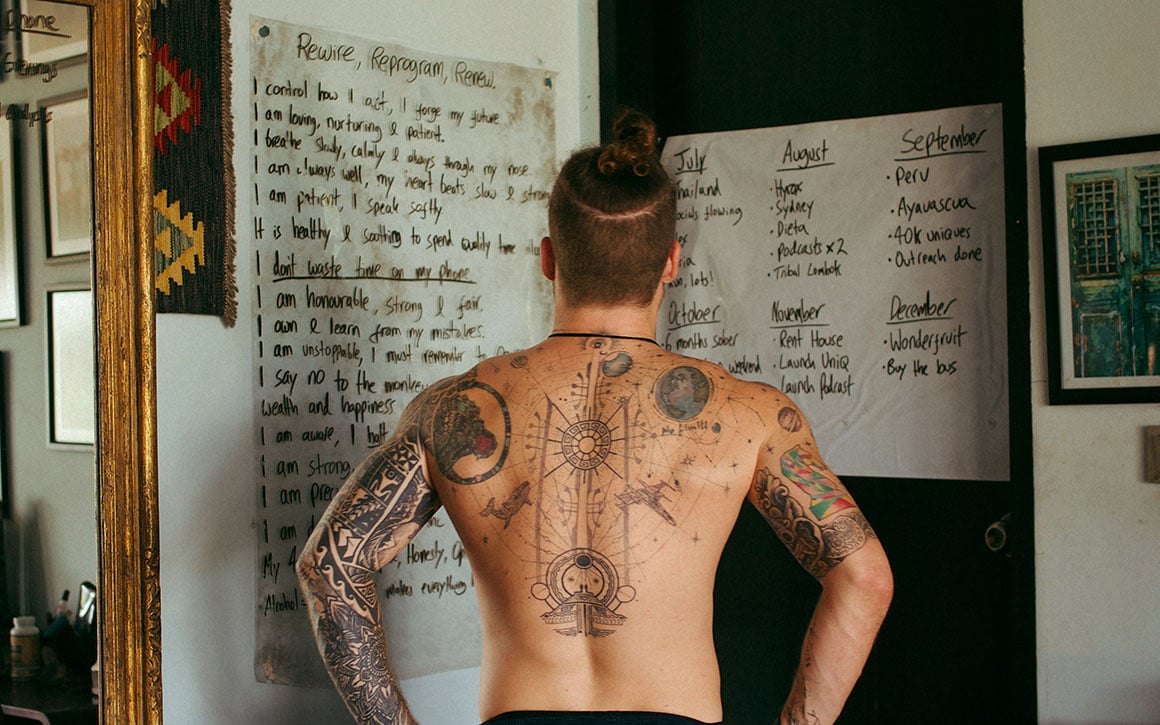 Man topless with tattoos looking at a list.