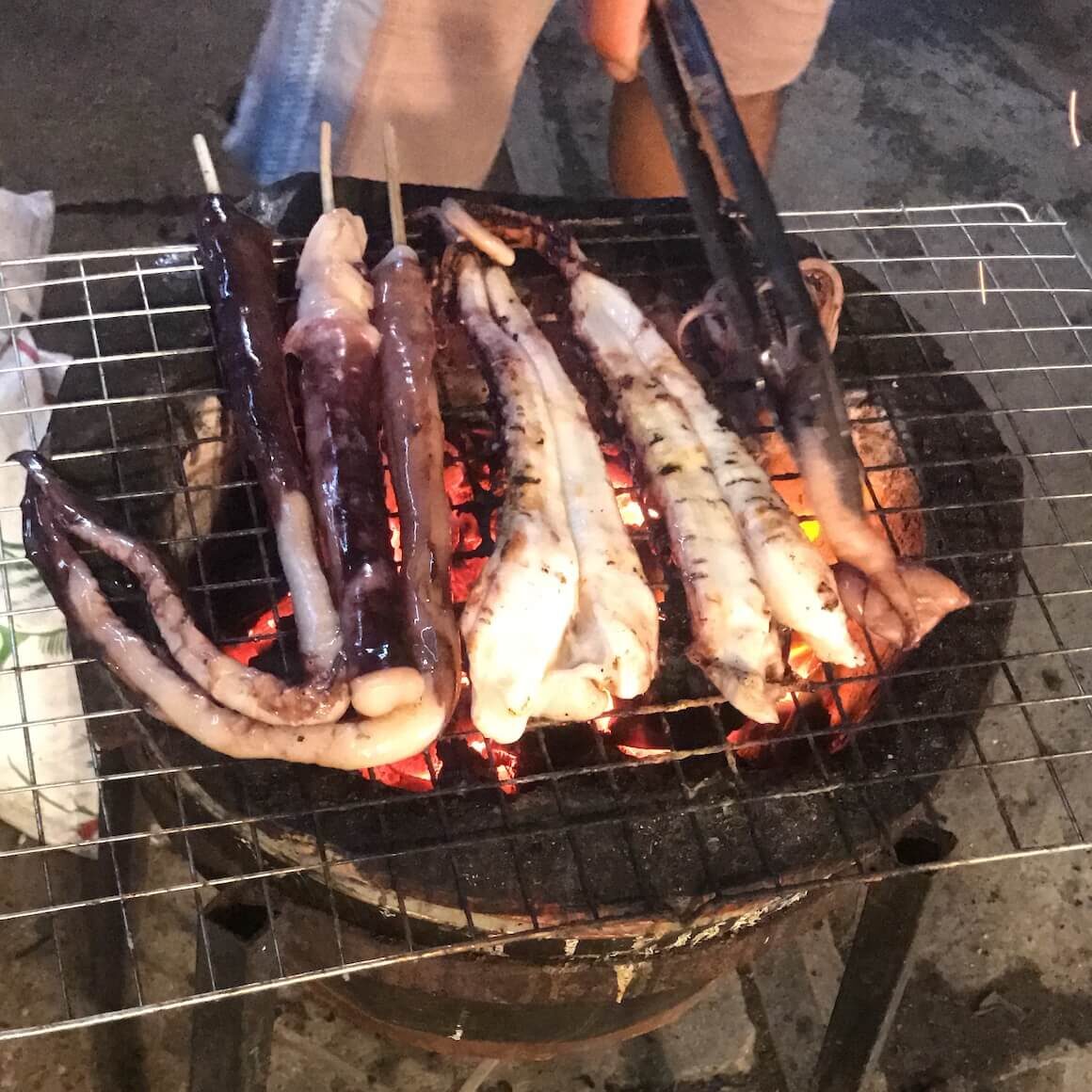purpleish octopus grilling over an open fire in thailand 