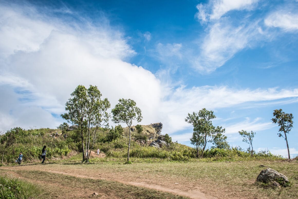 A couple walking down a hill, overlooking Phu Chi Fa's landscape in Thailand