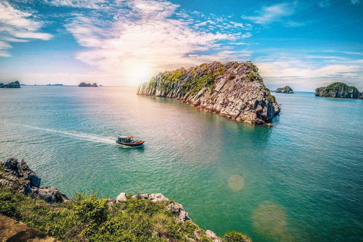Boat crossing South China sea and rock formations in Cat Ba Ha Long Bay, Vietnam
