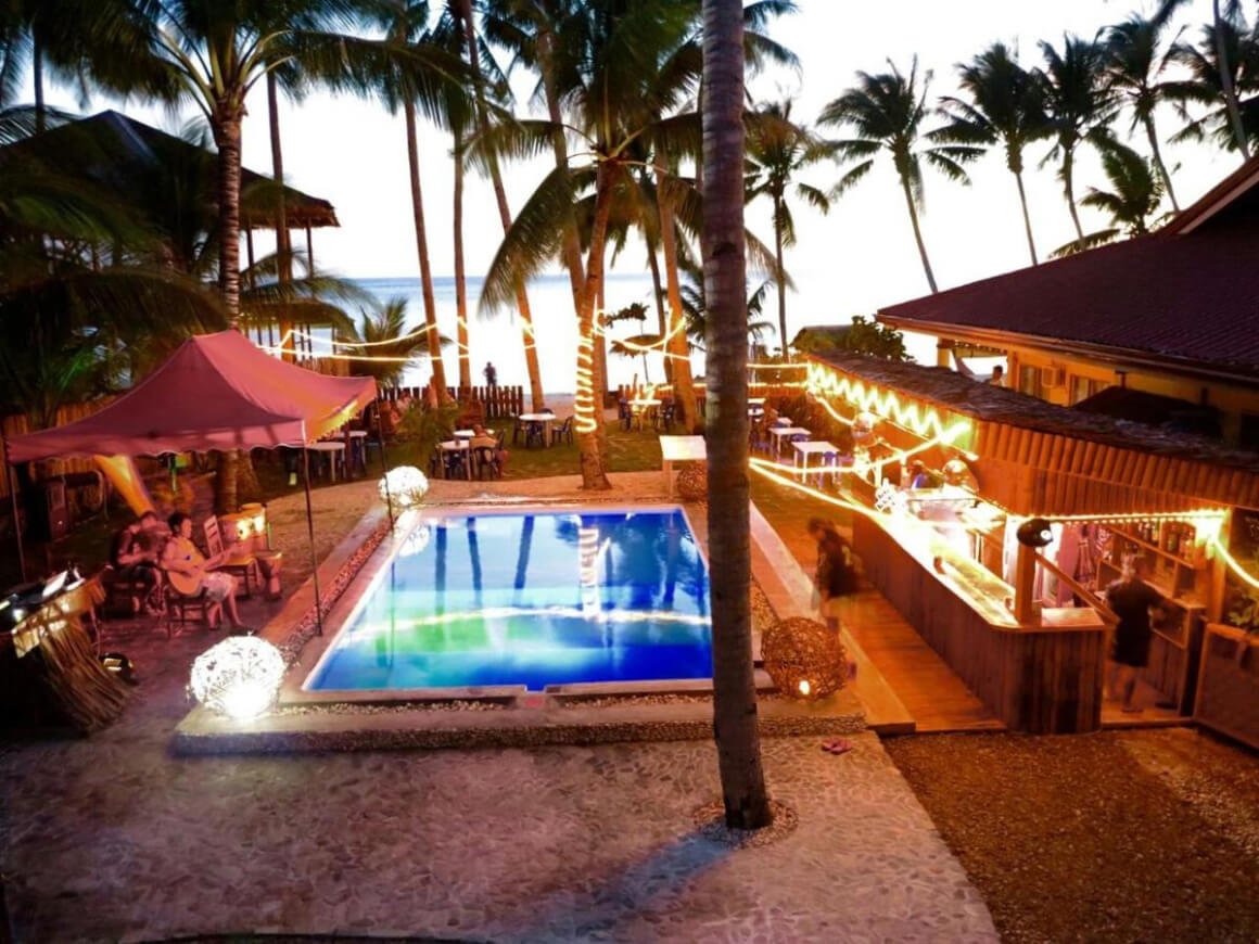Pool area with palm trees and cozy lighting in Apo Diver Beach Resort