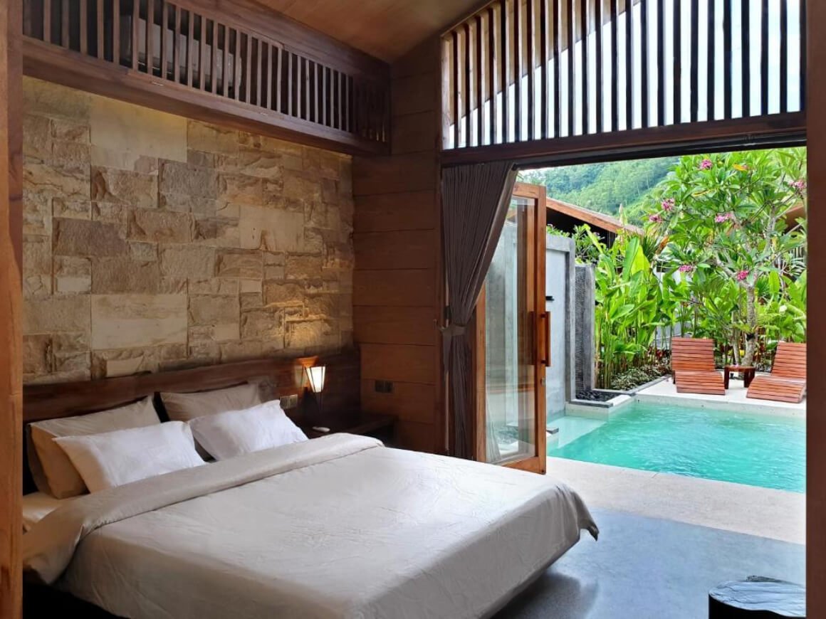 Bedroom interior with king-size bed and balcony with a pool view at Batatu Villas
