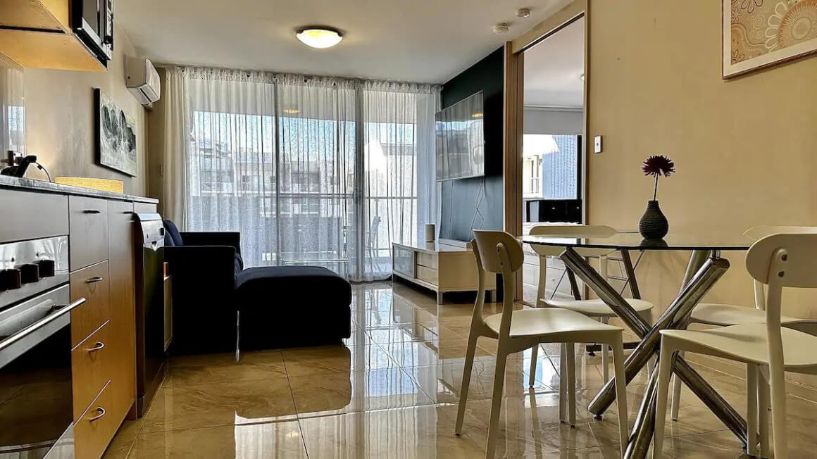 Kitchen, dining and living area in the Airbnb. Ceiling to floor windows at the back of the room.