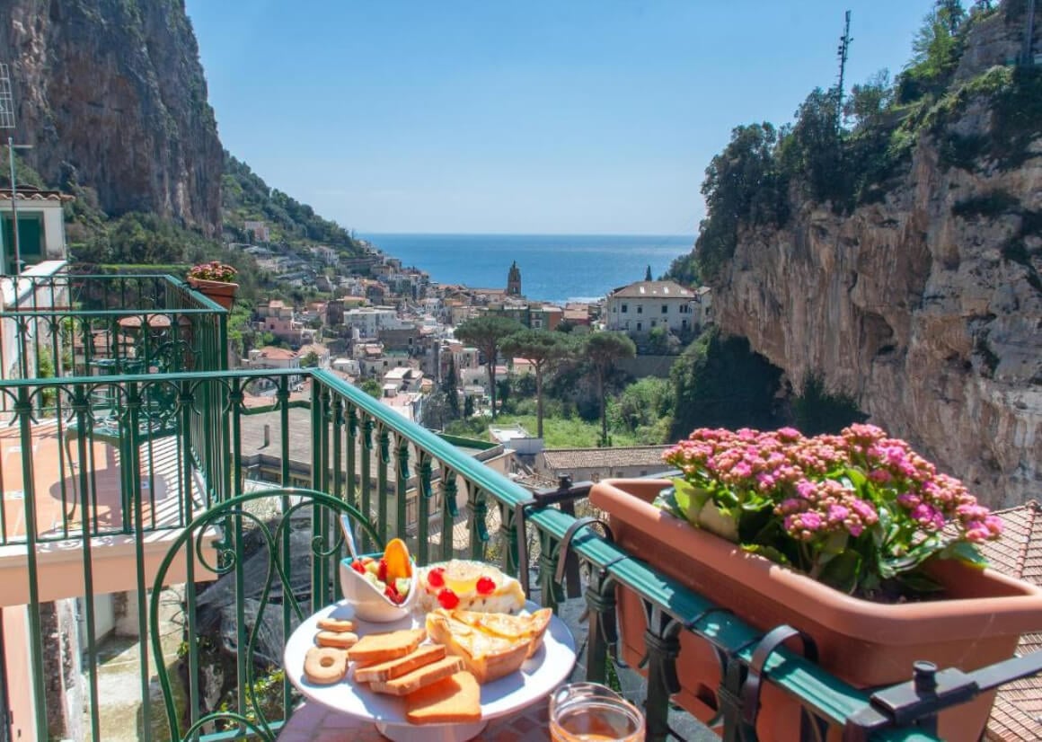 View from over the terrace over the Amalfi Coast cliffs, villages and out to the ocean. Beautiful breakfast on the table on the terrace