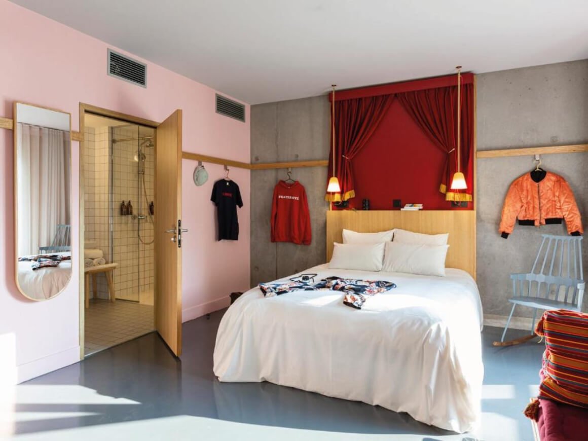 Beautiful, simple bedroom at MOB Hotel. It's got a pink, red and grey wall these. Low hanging lights over the bed and hip decor.